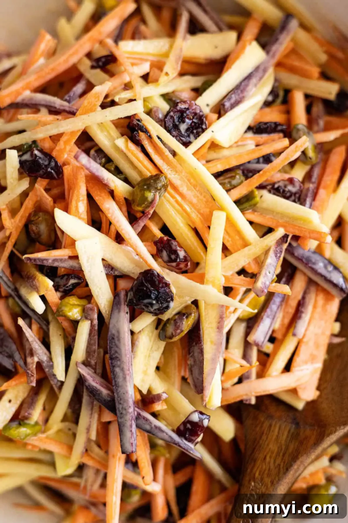Sunshine Carrot Slaw 5 Close up of the finished carrot salad, showing the vibrant orange carrots, green pistachios, and red cranberries coated in creamy dressing.