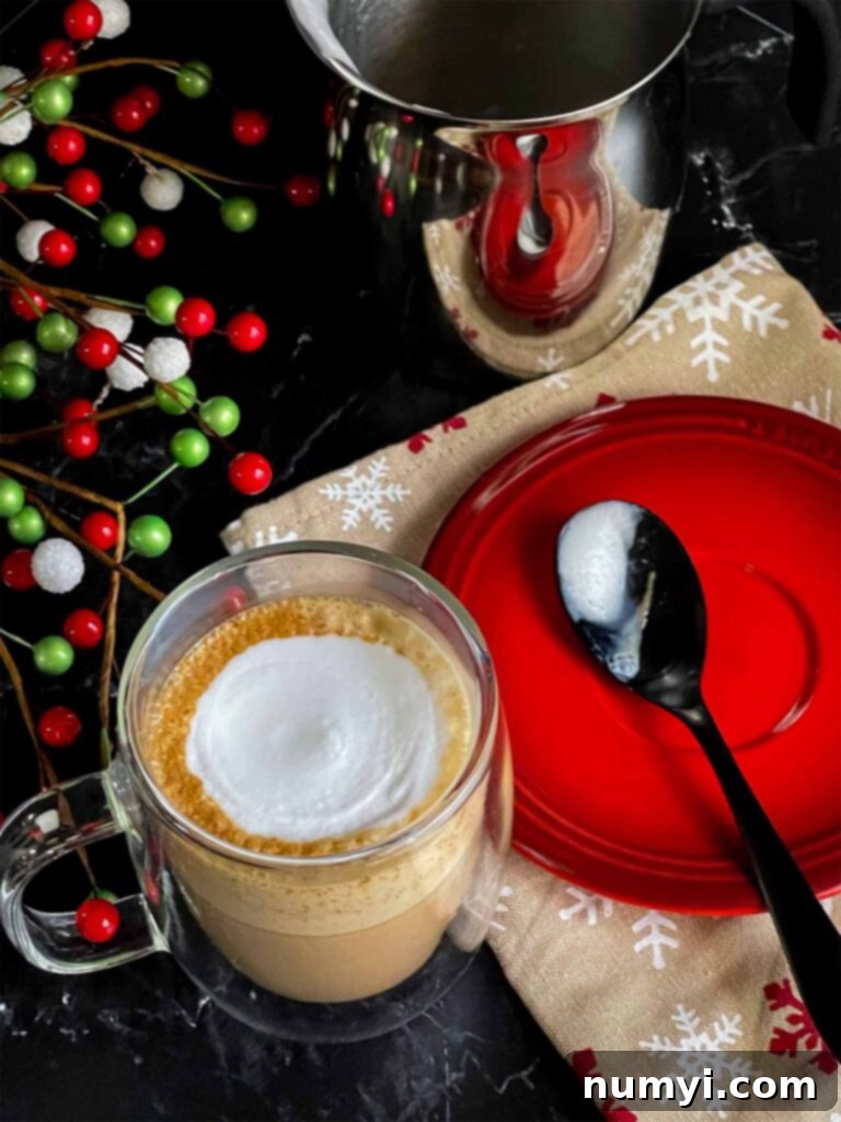 Craft Your Own Holiday Spice Flat White 10 A completed Holiday Spice Flat White in a clear glass mug, accompanied by a spoon on a small red plate.