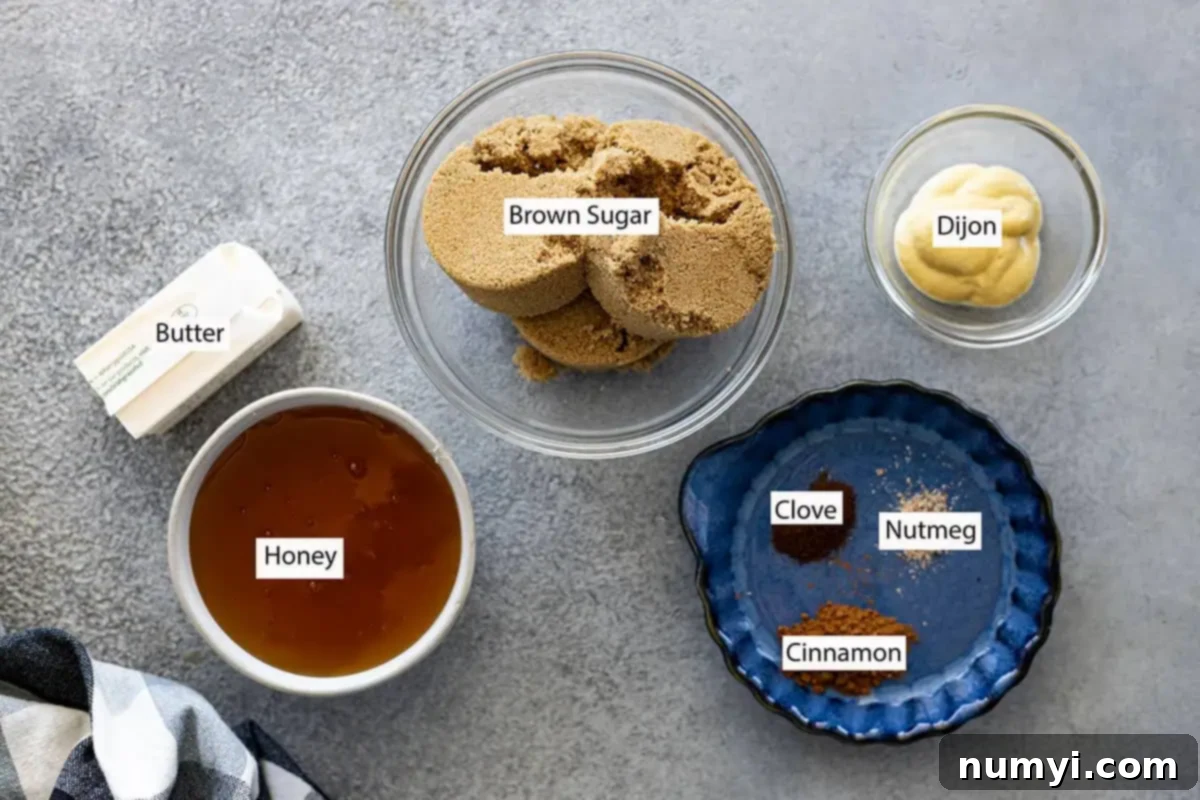 Close-up of ingredients for honey ham glaze: brown sugar, butter, honey, Dijon mustard, cinnamon, ground clove, and ground nutmeg laid out on a surface.