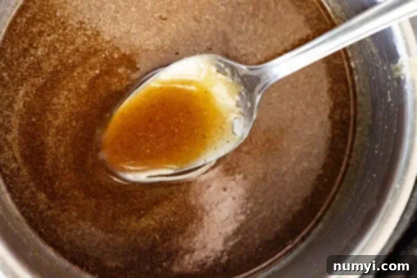 Overhead view of a spoon in the glaze, showing its smooth consistency after cooking.