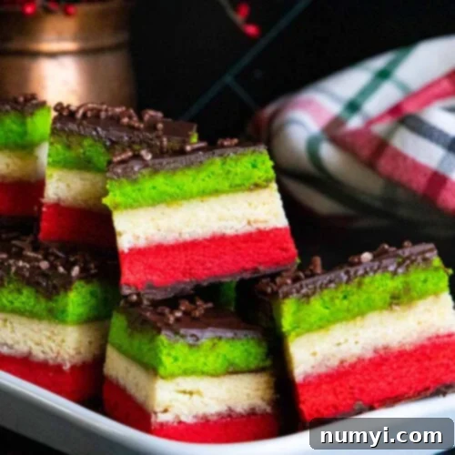 Italian rainbow cookies on a white tray, showcasing their vibrant colors and chocolate topping, ready to be enjoyed.