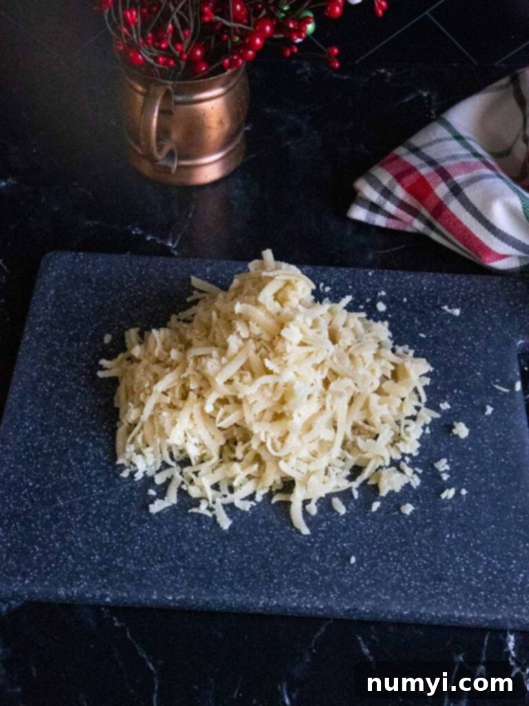 Finely shredded almond paste ready for mixing on a black cutting board, showcasing its ideal texture for easy incorporation into the batter.