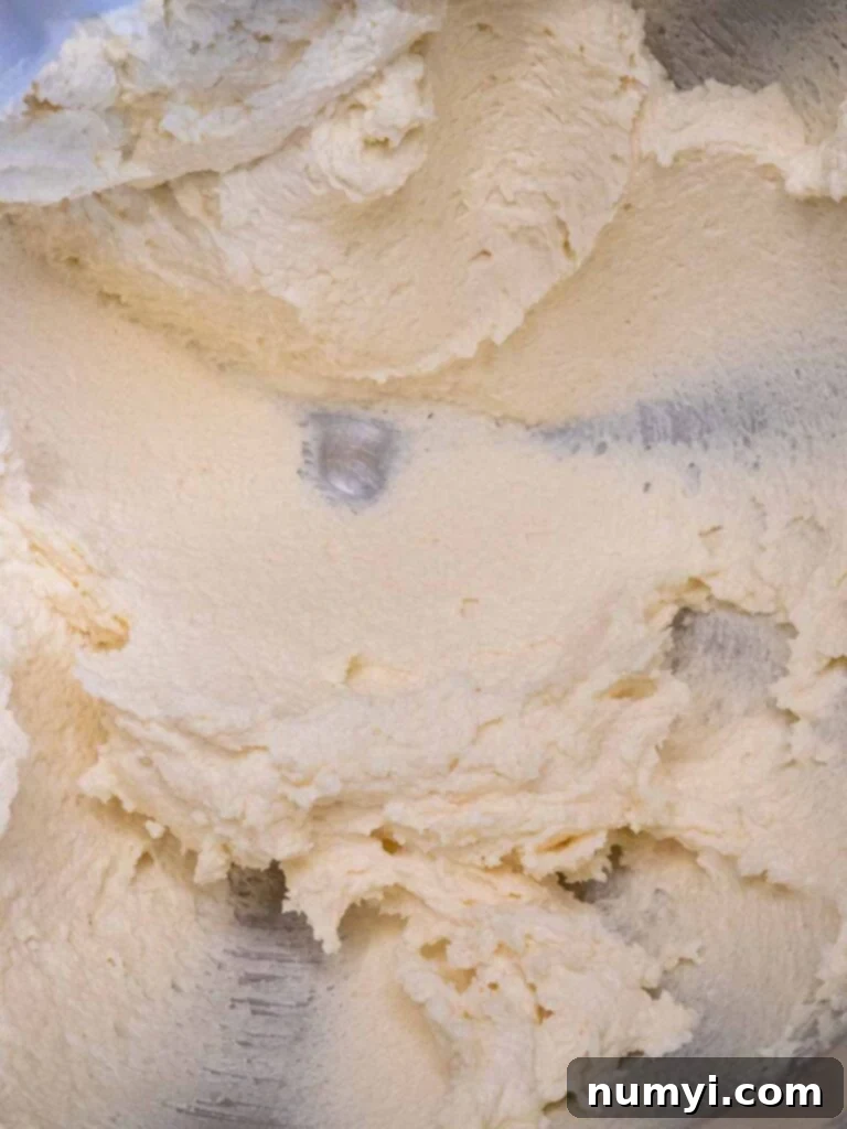 The perfectly creamed mixture of butter, almond paste, sugar, and salt in a stand mixer bowl, showing a light and fluffy consistency.