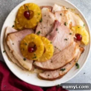 Overhead view of slices of ham on a plate with pineapple.
