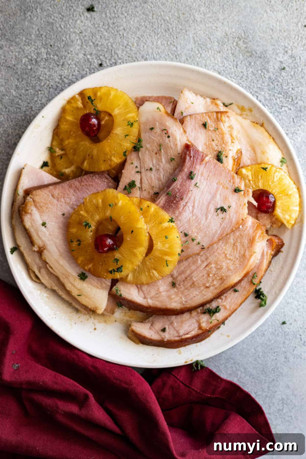 Overhead view of slices of ham on a plate with pineapple. 
