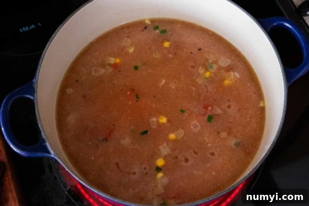 Stovetop Chicken Tortilla Soup 4 Ingredients for chicken tortilla soup cooking in a blue dutch oven