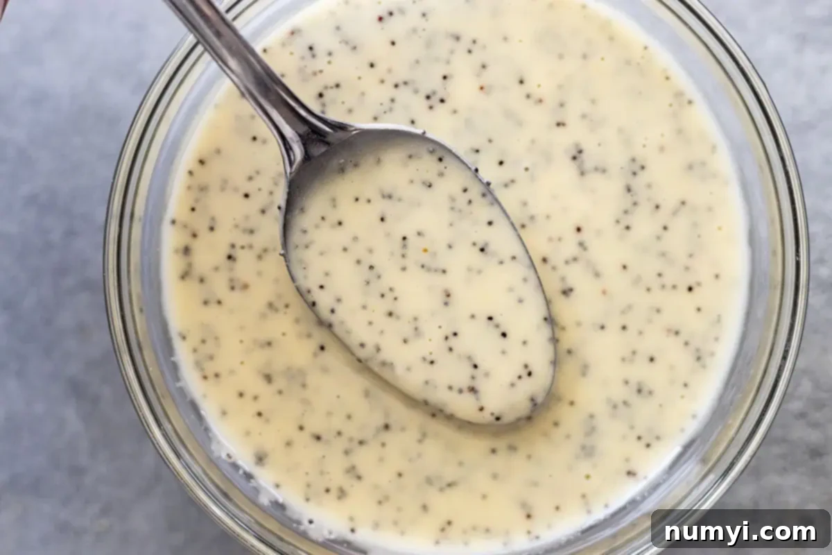 Overhead view of a spoon lifting up some dressing from a bowl. 