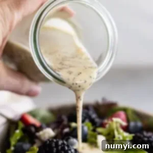 Bottle pouring dressing onto a berry salad.