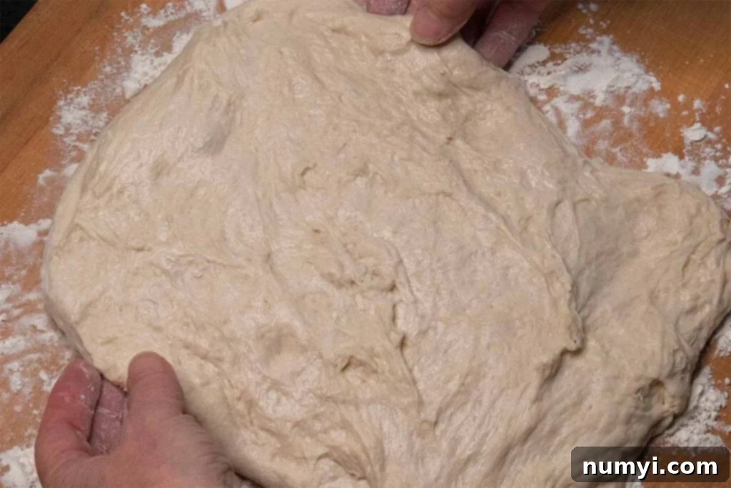 Skillfully laying out the soft bread dough into a flat rectangle on a lightly floured countertop.