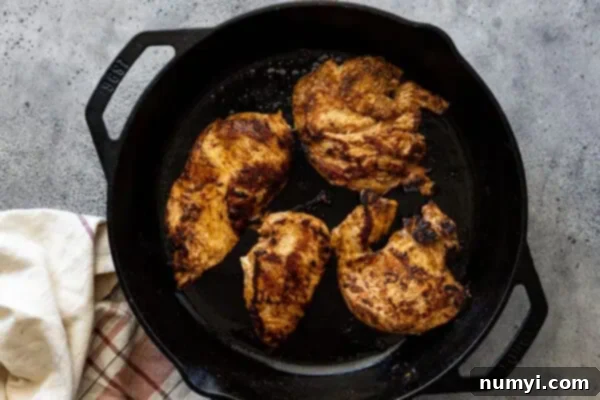Overhead view of cooked chicken in a cast iron skillet.