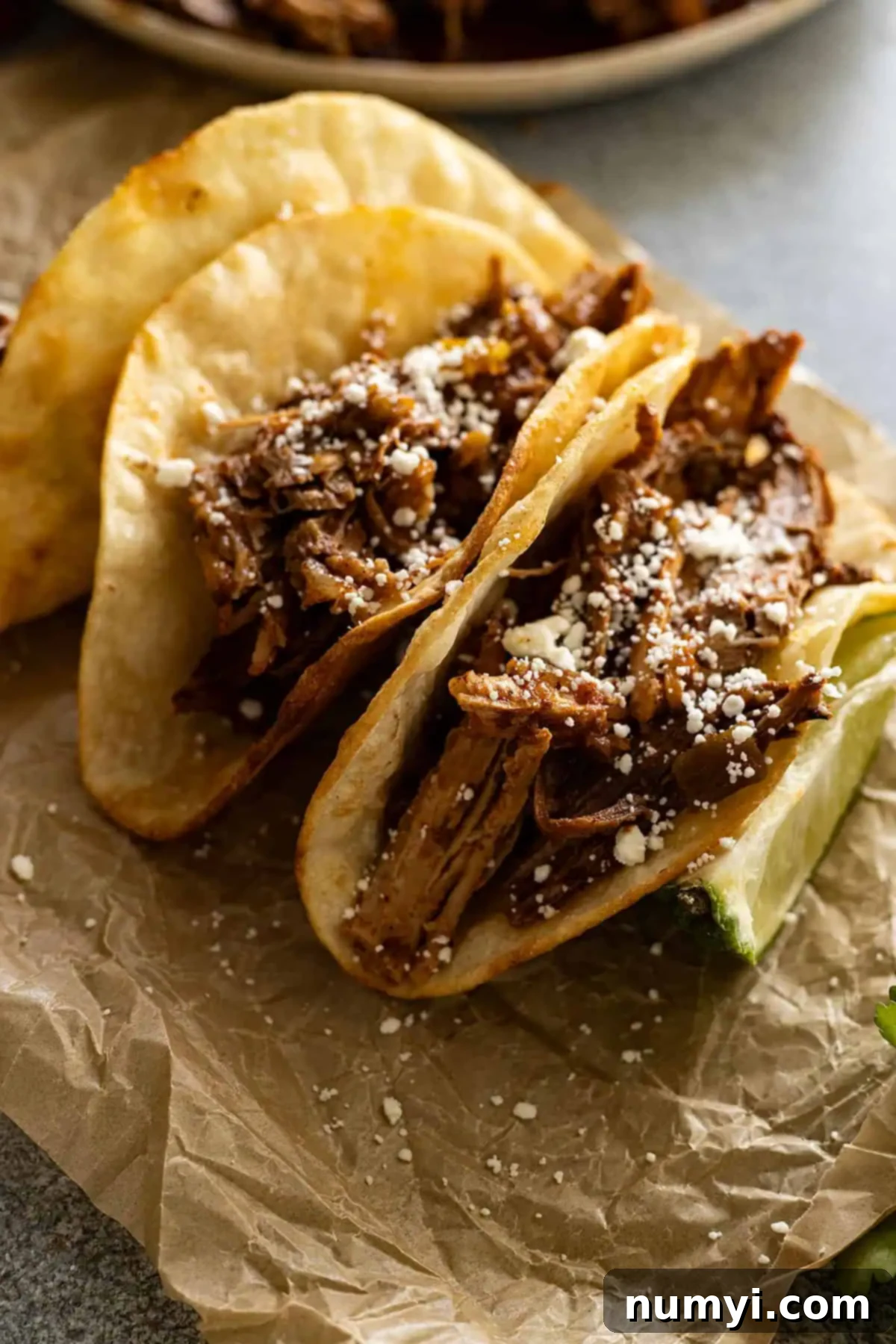 Close up of pork tacos sprinkled with cheese. 