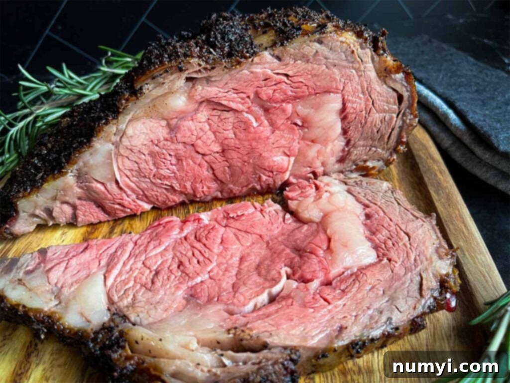 Closed Oven Prime Rib Roast 2 Perfectly sliced medium-rare prime rib roast garnished with fresh rosemary on a wooden cutting board.