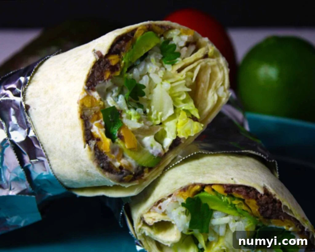 Vibrant Veggie Burrito 2 A vibrant vegetarian burrito, expertly cut in half, showcasing layers of fresh ingredients, rests invitingly on a blue platter.