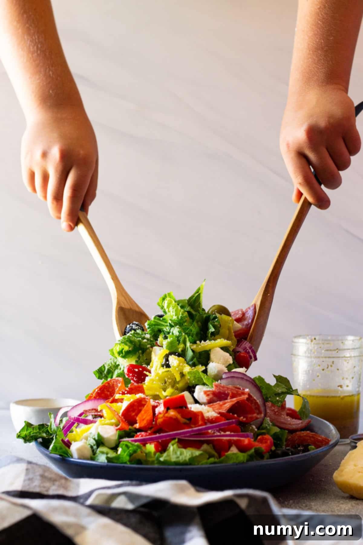 Big Italian Deli Salad 4 Close-up of a large bowl of Antipasto Salad with salad tongs, ready for tossing before serving.