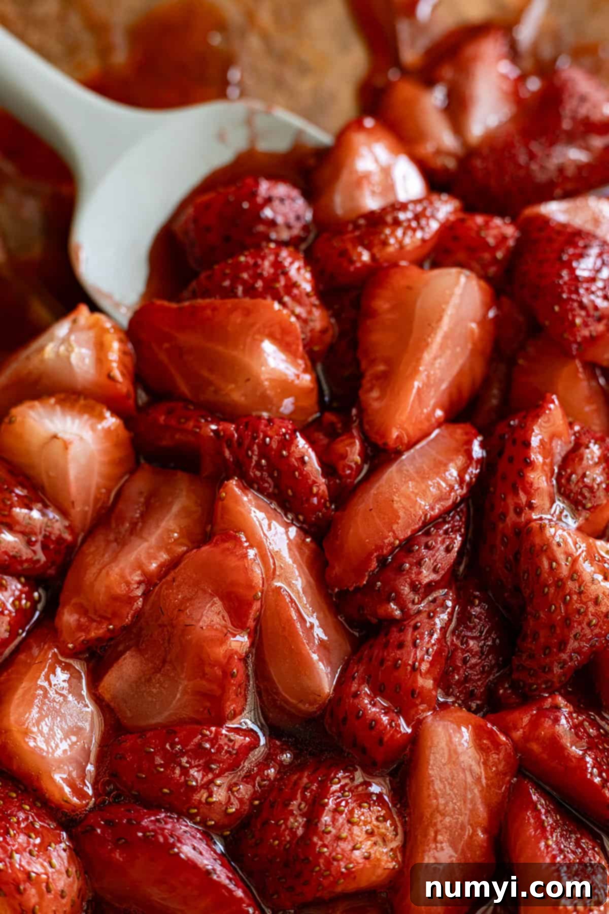 Close up of glossy, perfectly baked strawberries ready to be served, showcasing their vibrant color and jammy texture.