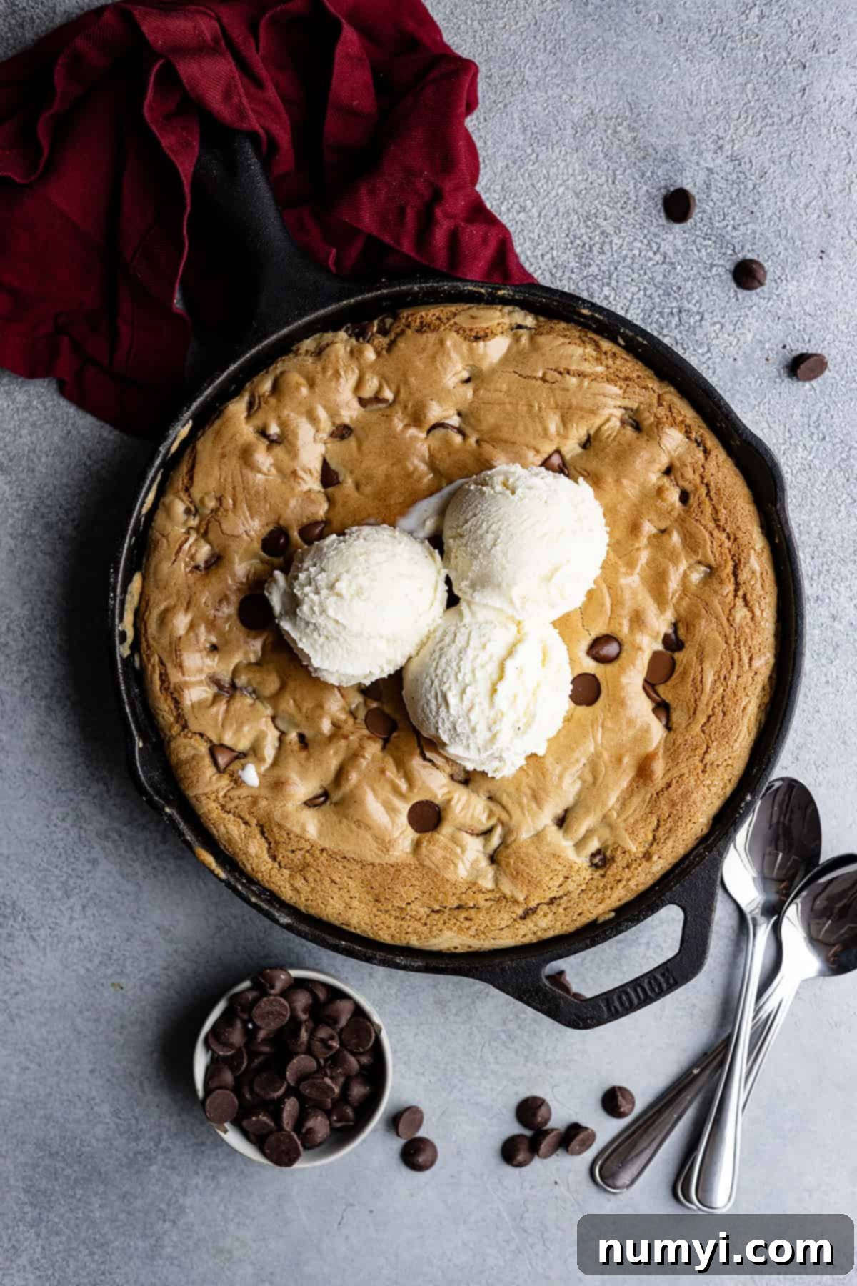 Overhead view of chocolate chip skillet cookie with vanilla ice cream on top ready to eat. 