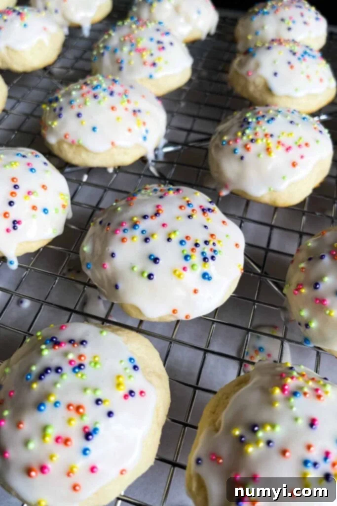 Freshly glazed Italian ricotta cookies with colorful sprinkles drying on a wire rack