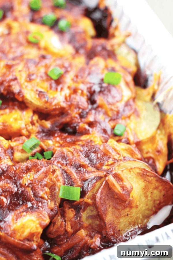 cheddar and bacon baked sliced potatoes in a baking tray garnished with chives