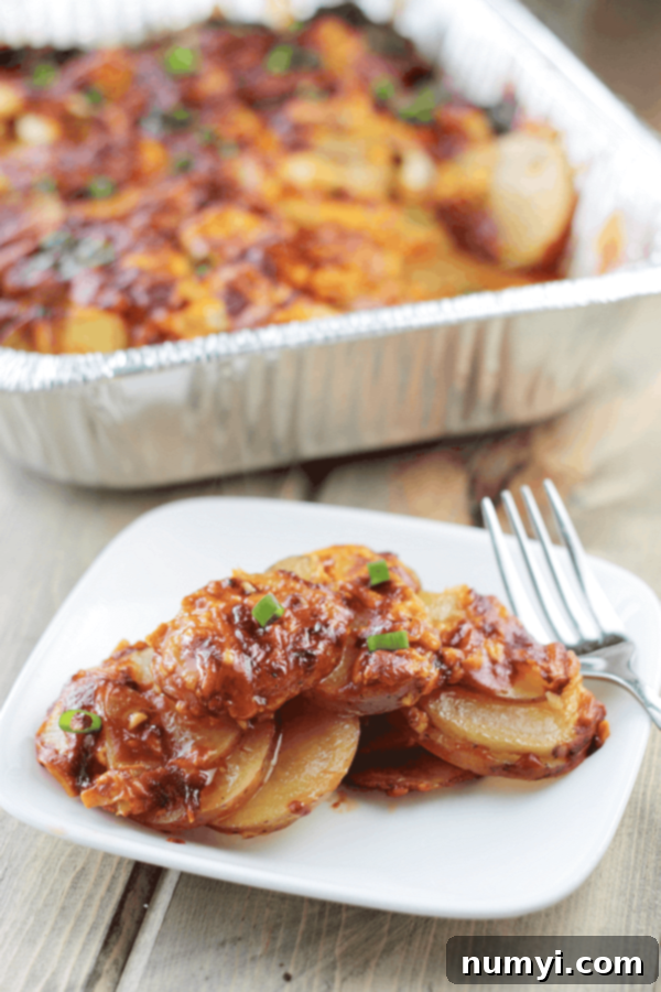 a white plate of cheddar and bacon covered sliced potatoes in front of a full try of them out of focus