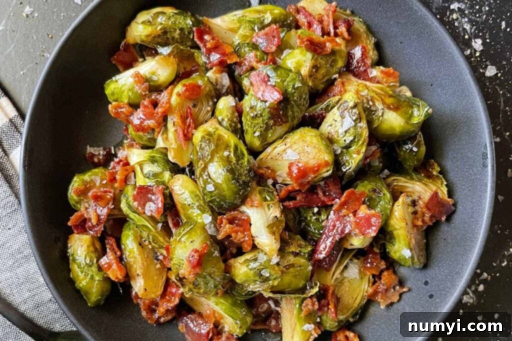 A bowl of roasted brussels sprouts with honey butter and crispy bacon, ready to serve.