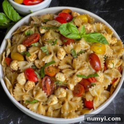 Pesto pasta Caprese salad in a white bowl.