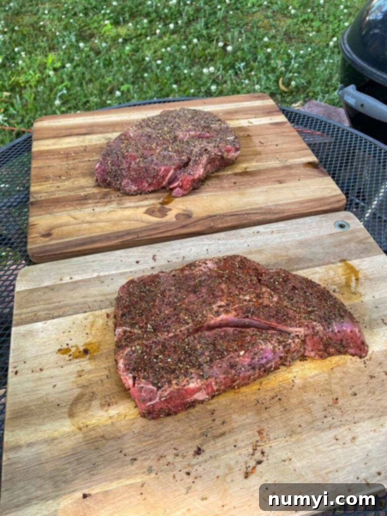 two chuck roasts with rub applied about to go onto a smoker.