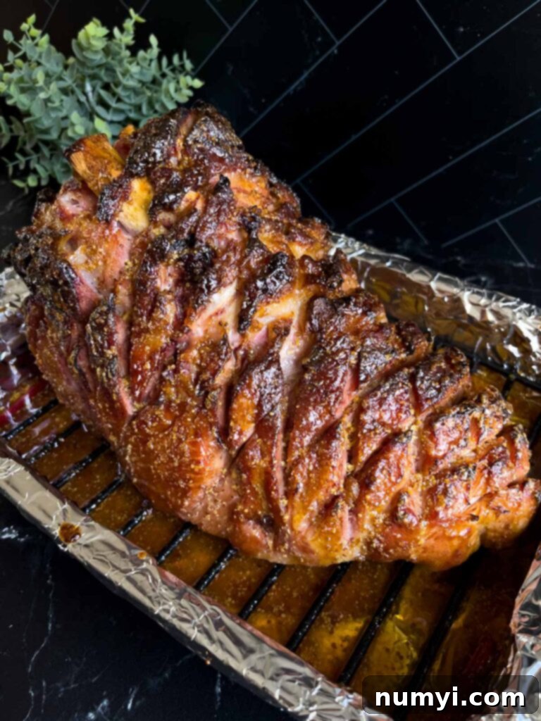 The baked brown sugar glazed ham, perfectly caramelized and glistening, sitting in its roasting pan, fresh out of the oven.