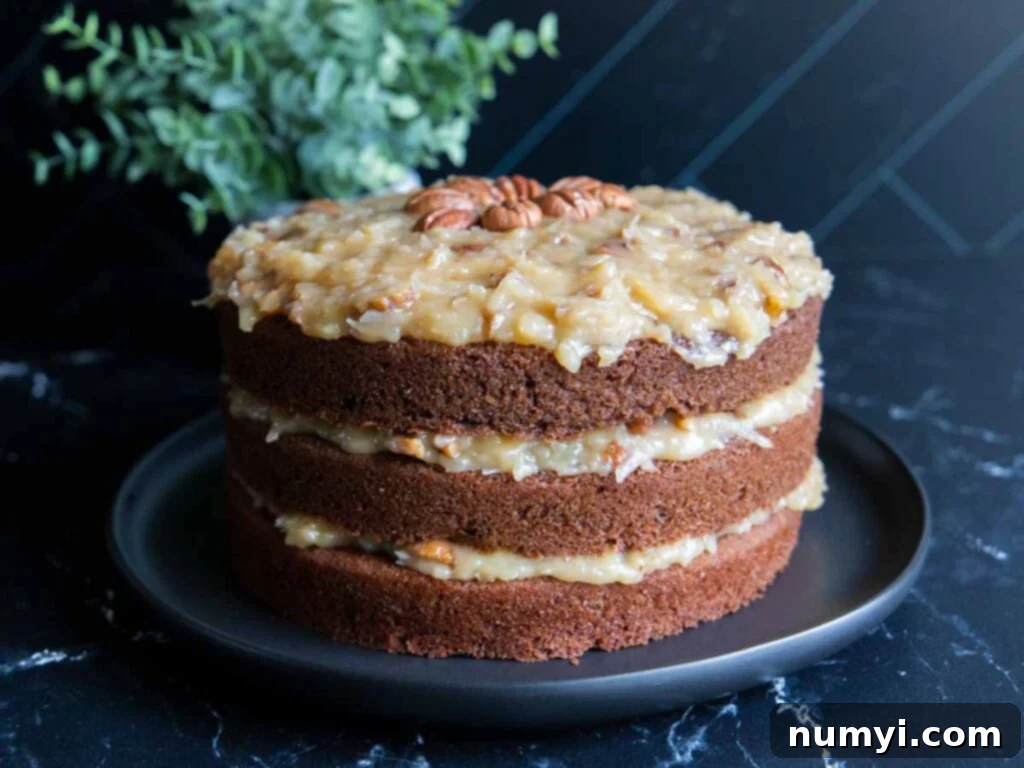 A beautifully presented whole Baker's German Chocolate Cake on a black plate, showcasing its rich chocolate layers and generous coconut pecan frosting.