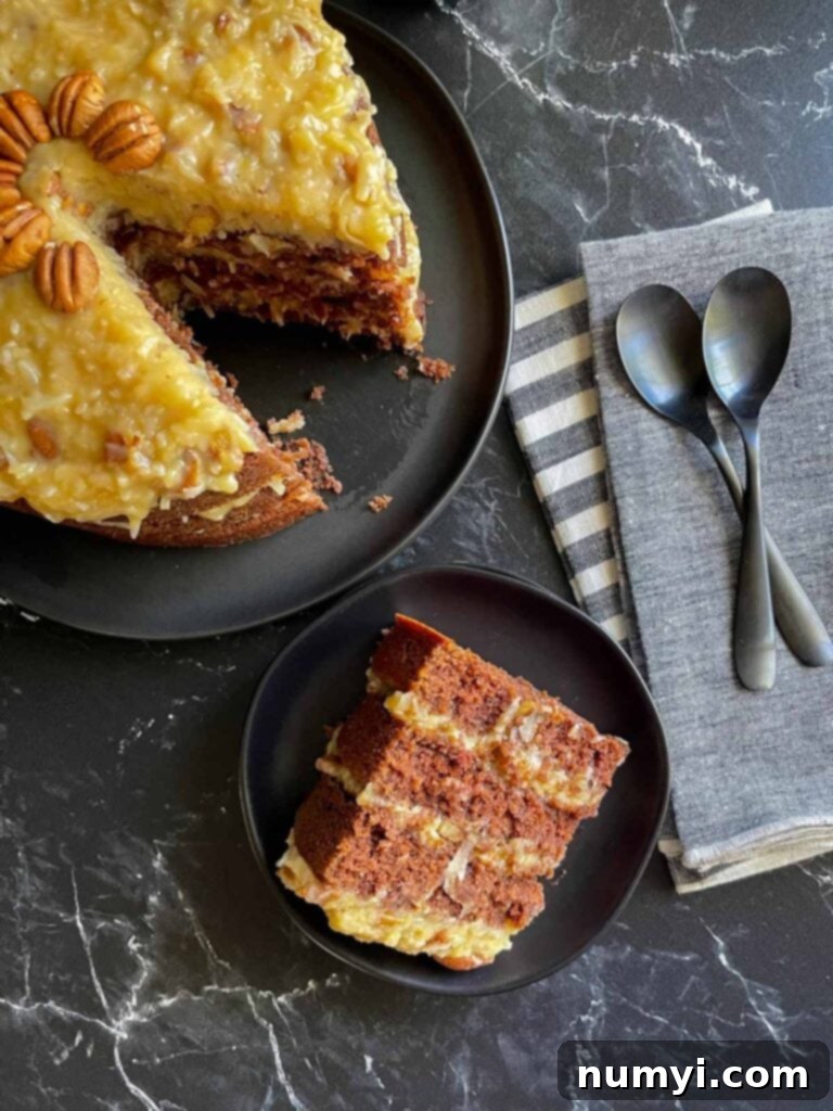A perfect slice of original Baker's German Chocolate Cake, showcasing multiple moist chocolate layers and thick, rich coconut pecan frosting, on a black plate.