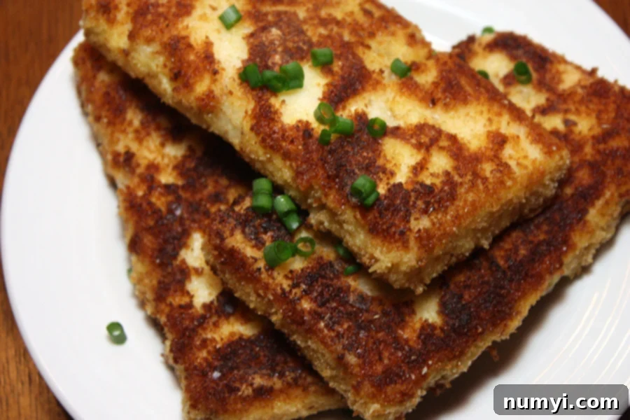 Fried Grit Cakes on a white plate garnished with green onion.