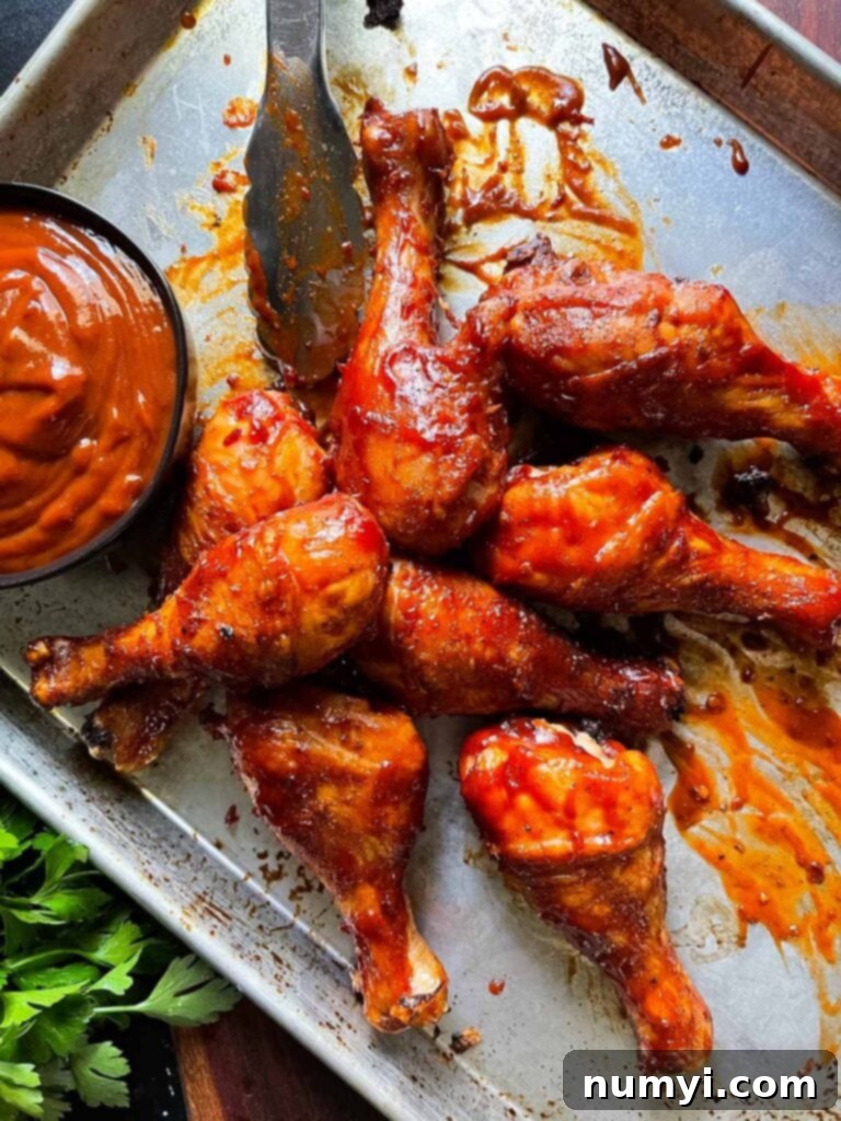 Barbecue chicken legs grilling on a sheet pan, showing indirect heat setup.
