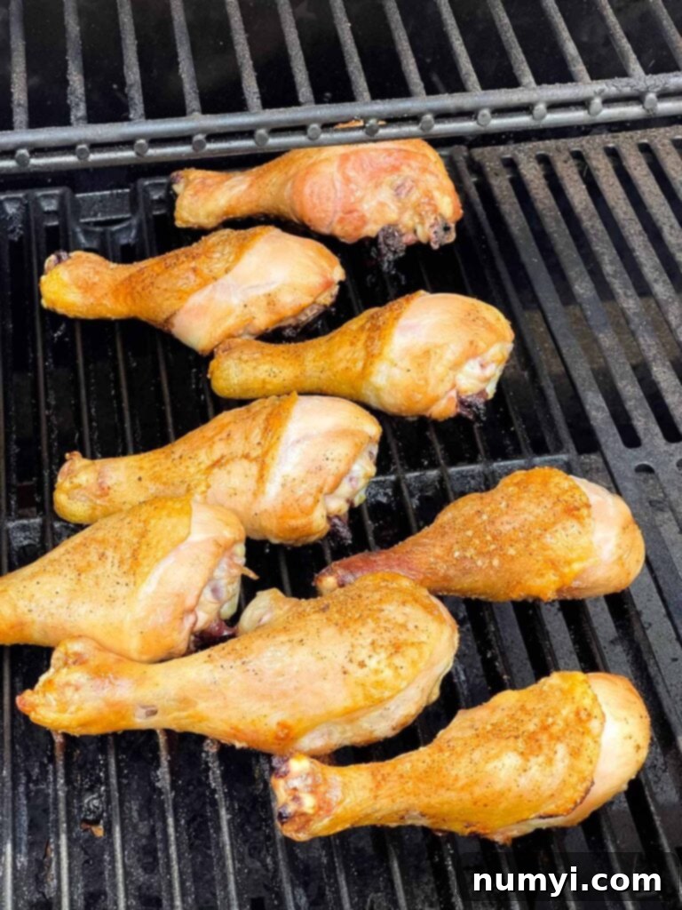 BBQ chicken legs on the grill, showing crispy skin before sauce application.
