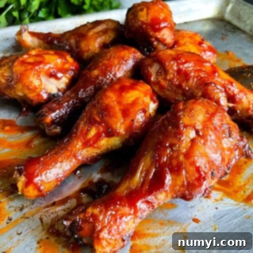 Bbq chicken legs on a baking sheet, glazed with sauce.