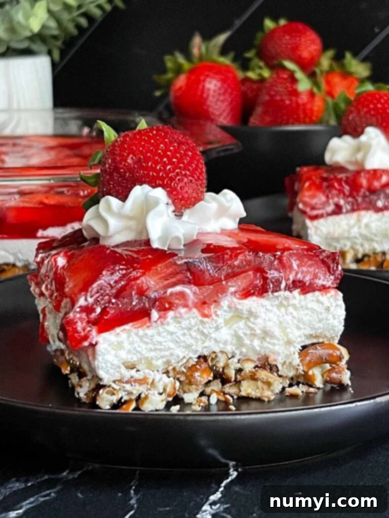 A slice of strawberry pretzel salad on a black plate.