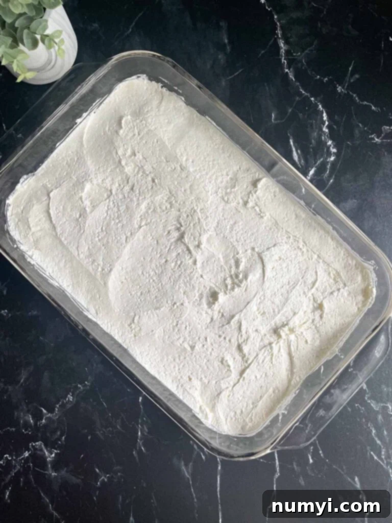 Whipped cream and cream cheese topping on top of a pretzel crust.