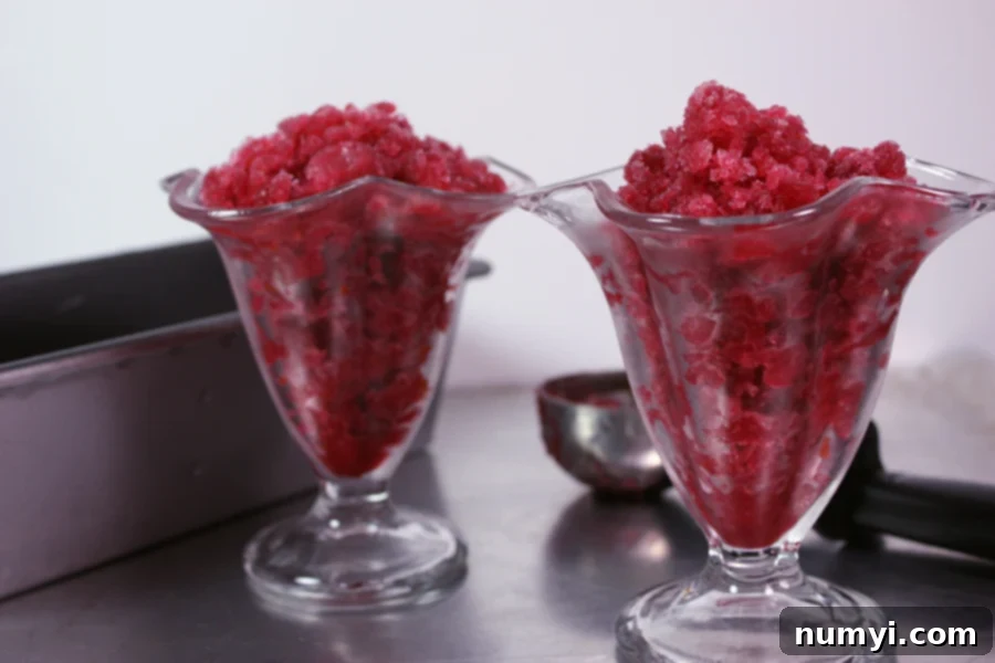 Multiple servings of blood orange granitas in sorbet glasses, arranged on a metal sheet pan.
