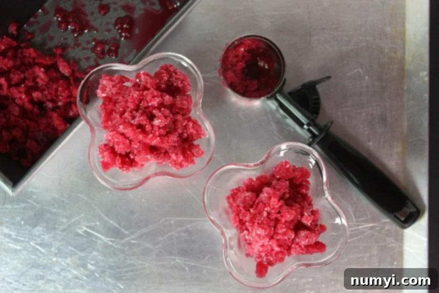 A metal sheet pan filled with blood orange granita, showcasing its icy, scraped texture.