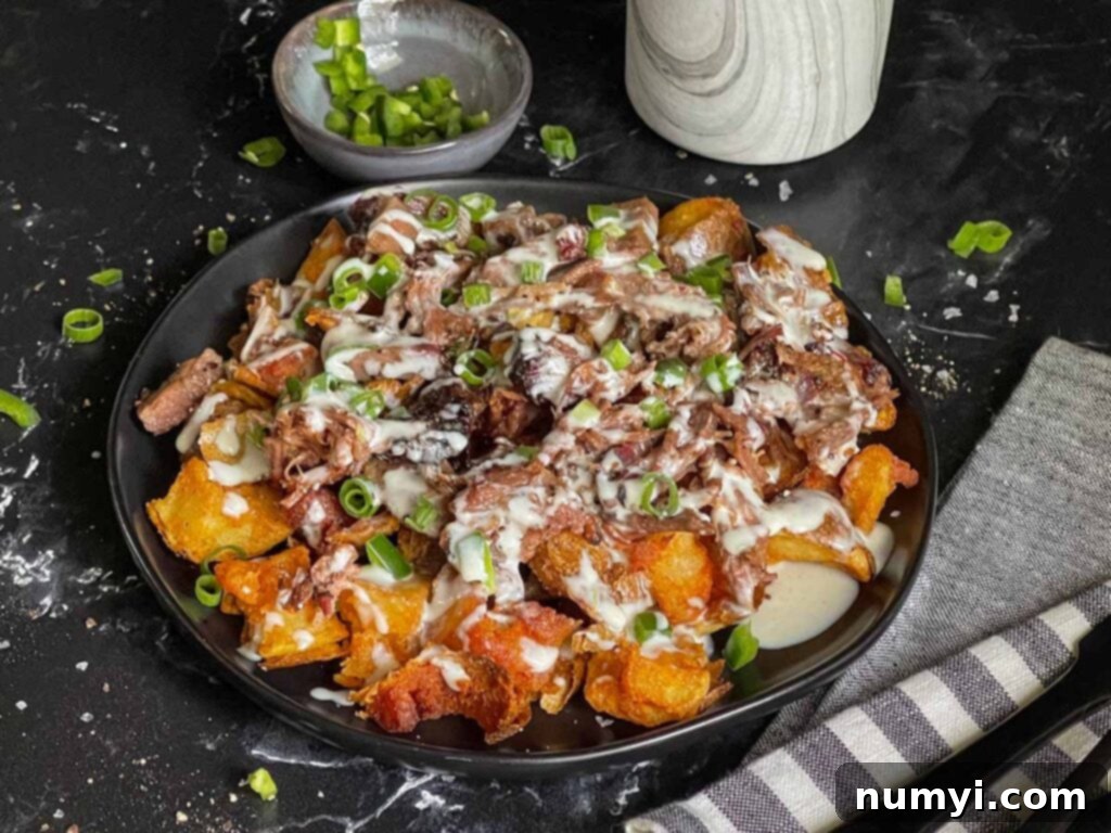 Loaded potato bites on a black plate, showcasing crispy potatoes, smoky brisket, and melted queso.