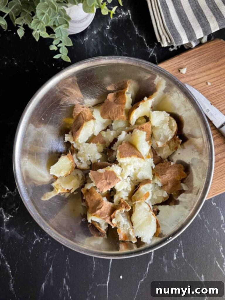 Broken up baked potato in a metal bowl, ready for frying to achieve maximum crispiness.