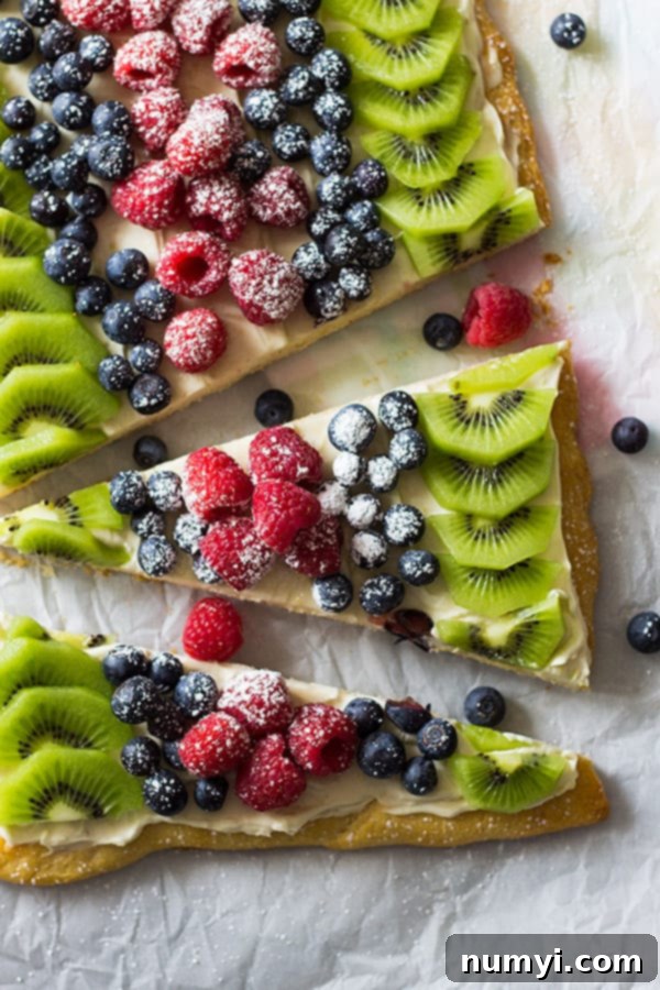 A beautifully arranged easy fruit pizza made with a crescent sheet, topped with sweetened cream cheese and a variety of colorful fresh fruit, perfect for summer gatherings.