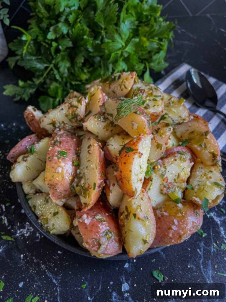 A black plate presentation of the finished herb potato salad, ready to be served.