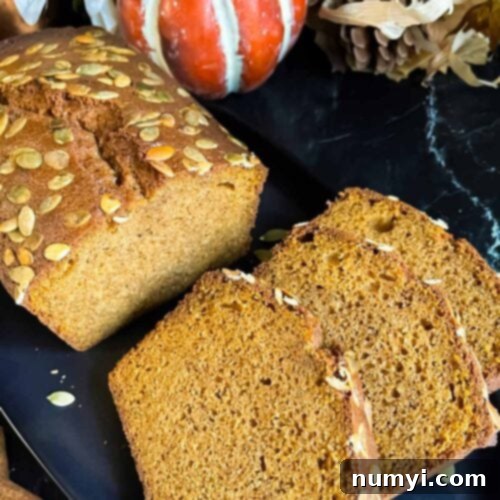 Baked pumpkin bread, sliced, on a dark platter.