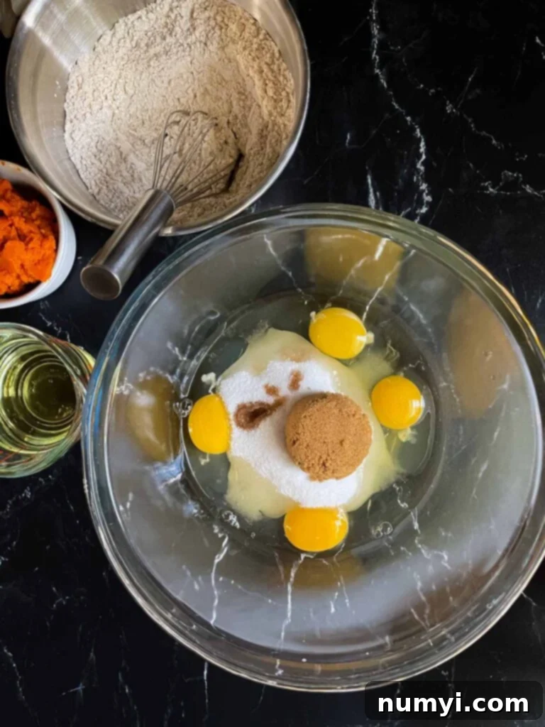 Eggs, sugars, and vanilla extract for pumpkin bread in a glass bowl.