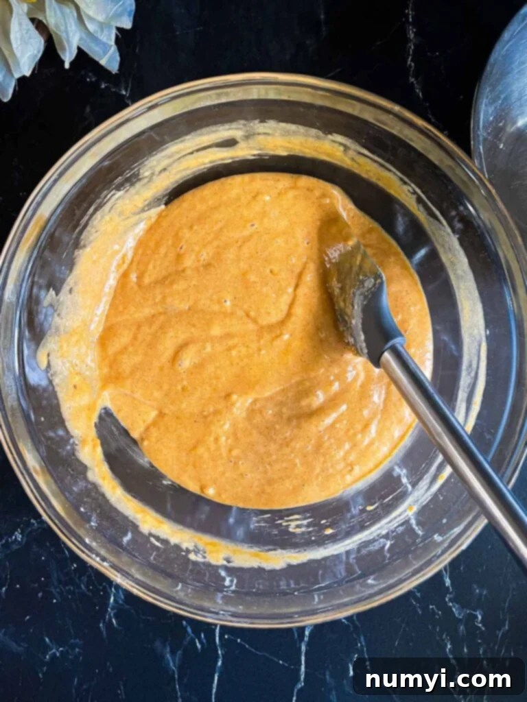 Pumpkin bread batter mixed together in a glass bowl.