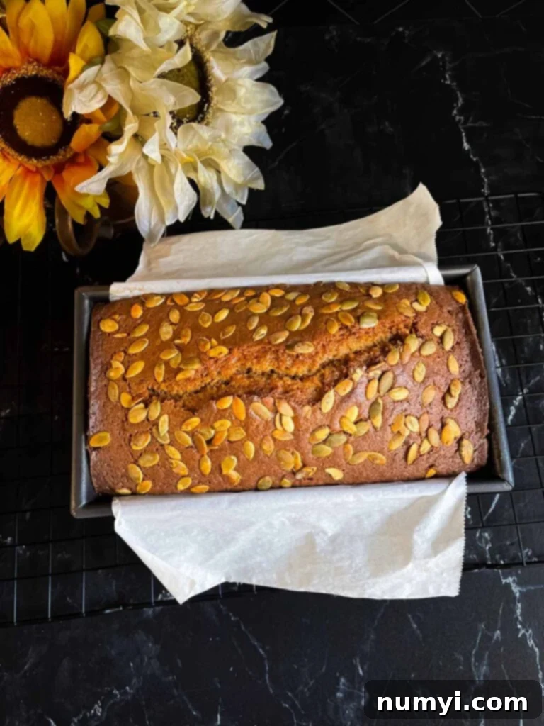 Baked pumpkin bread in a loaf pan on a dark surface.