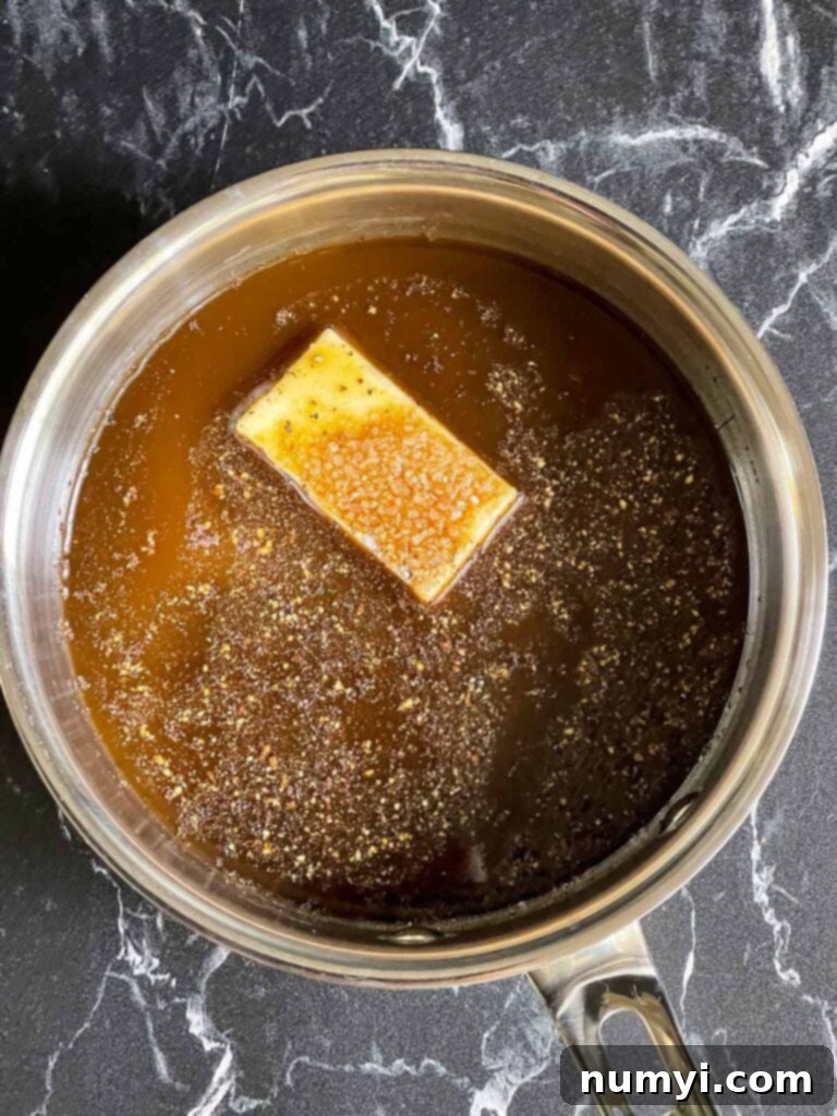 The mop ingredients, including Worcestershire sauce, butter, apple cider vinegar, salt, and pepper, in a saucepan.