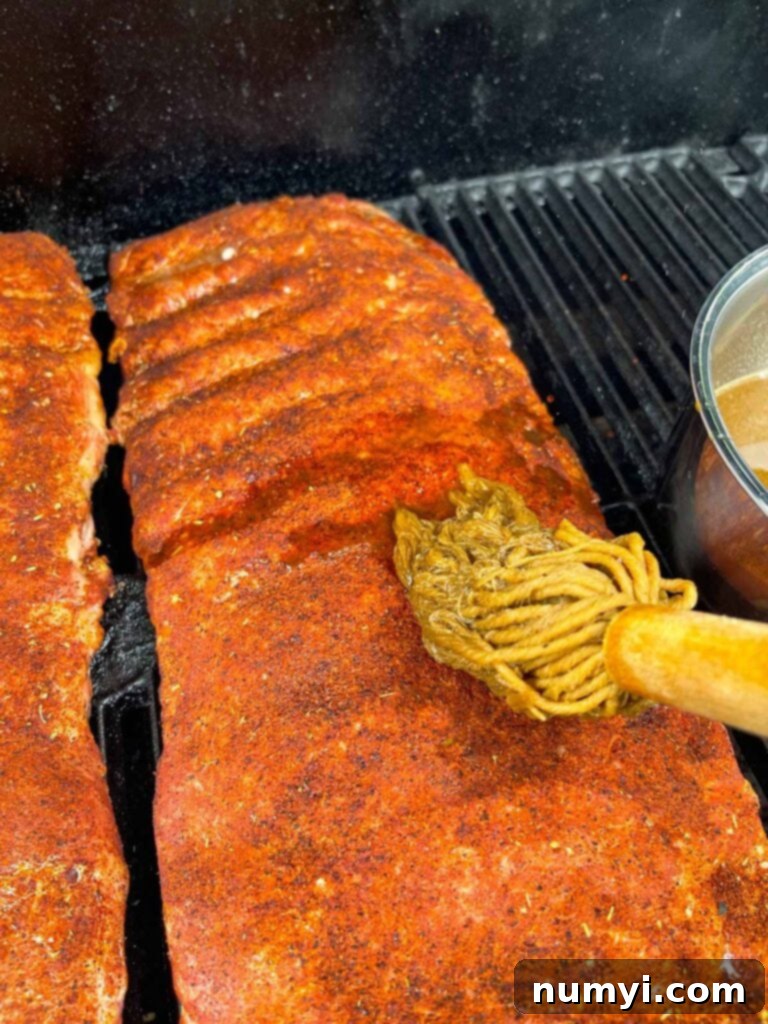 Applying the mop sauce to the St. Louis style ribs on the smoker.