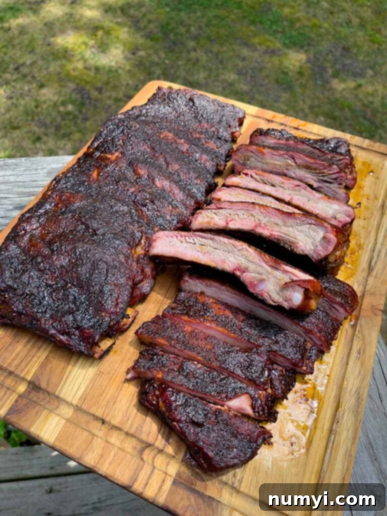 Two racks of smoked ribs on a cutting board, one expertly sliced into individual ribs.