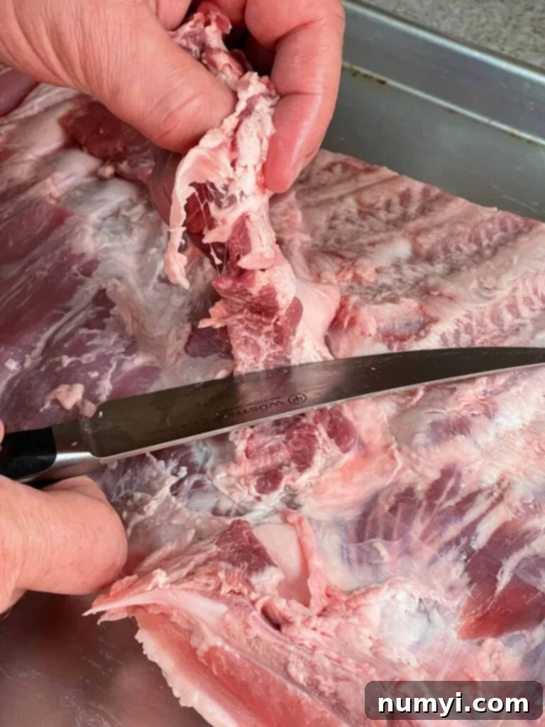 Trimming the diaphragm from the back of a rack of ribs.