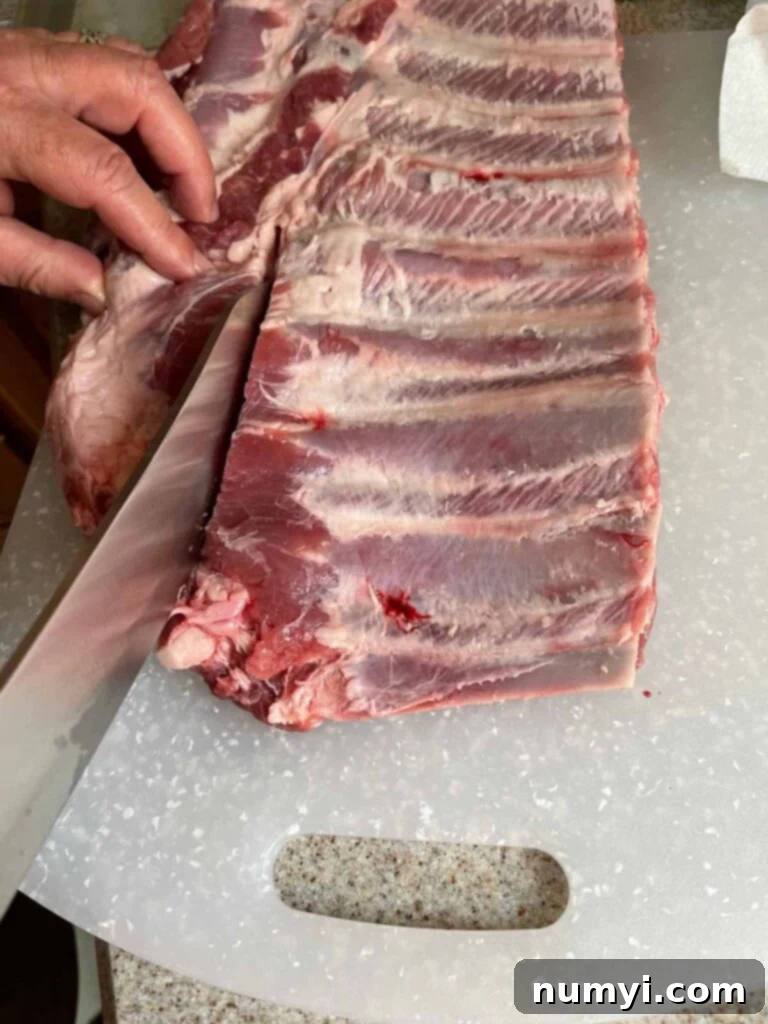 Removing the brisket bone and ribs tips from a rack of spare ribs to create a St. Louis cut.